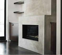 an empty living room with a fireplace and shelves