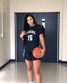 a female basketball player is holding a ball in her hand and posing for the camera