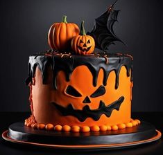 a decorated halloween cake with pumpkins and bats on top, sitting on a black surface