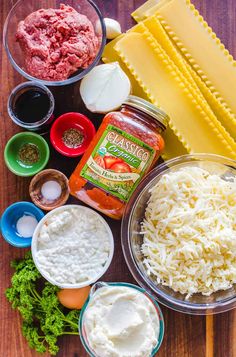 ingredients to make pasta laid out on a wooden table including cheese, sauces and meatballs