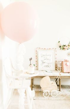 a baby's room with pink balloons and a white crib in the background