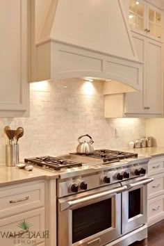 a stove top oven sitting inside of a kitchen next to white cabinets and counter tops