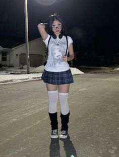 a girl in a school uniform is standing on the street with her hands behind her head