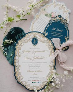 the wedding stationery is blue and gold with white flowers on it, along with other items