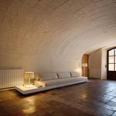 a living room with a couch and lamp on the floor next to a doorway that leads into another room