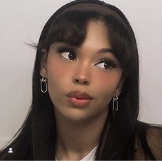 a close up of a person with long black hair and large hoop earrings on her head