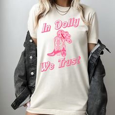 We love how our "In Dolly We Trust" Dolly Parton graphic tee turned out!  The perfect gift for any Dolly Parton fan or music lover!  The girly cowgirl design is right on trend.  Printed on super soft, ultra high quality Bella & Canvas Tee.   **All designs are printed direct to garment ensuring the highest quality of color, design, and longevity. Printed in our print shop located in Cleveland, Ohio. We are able to provide our customers lighting fast shipping and the ability to alter any image/des Dolly Parton Graphic, In Dolly We Trust, Dolly Parton Shirt, Cowgirl Shirts, Coastal Cowgirl, Bella Canvas Tees, Cow Girl, Cleveland Ohio, Dolly Parton