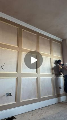 a man is painting the walls in an empty room with wood paneling and white paint