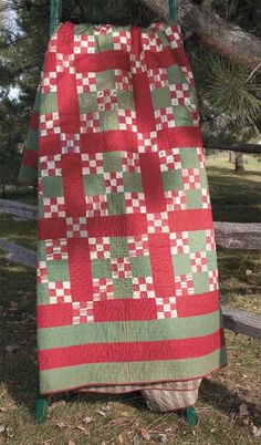 a red and green quilt hanging from a tree