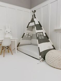 a teepee tent sitting on top of a white floor next to a table and chair