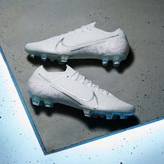 a pair of white nike soccer cleats sitting on top of a cement floor