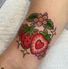 a strawberry tattoo on the left arm with cherries and leaves around it's heart