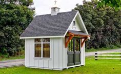 a small white shed sitting on top of a lush green field