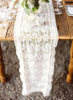 an image of a table setting with lace on it and flowers in vases at the end