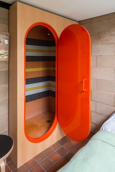 a room with a bed and an orange cabinet next to a wall that has stripes on it