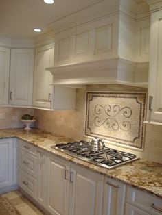 a kitchen with white cabinets and marble counter tops, along with a stove top oven