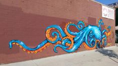 an octopus mural painted on the side of a building in front of a brick wall