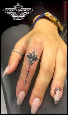 a woman's hand with tattoos on it and a lotus tattoo on the ring finger