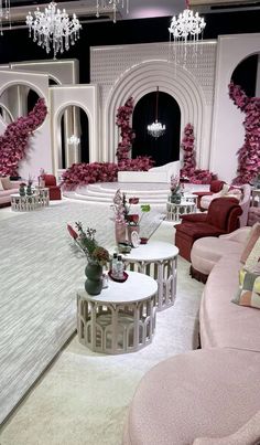 a living room filled with lots of furniture next to a chandelier covered in pink flowers