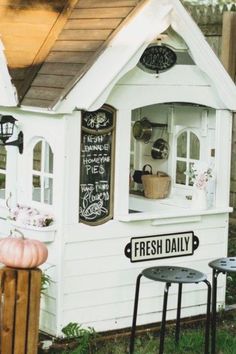 a small white dog house with chalkboard writing on the door and windows that says fresh daily