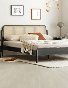 a bed sitting on top of a white floor next to a lamp and pictures above it