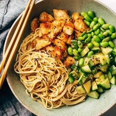 a bowl filled with noodles and vegetables next to chopsticks