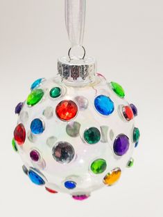 a multicolored glass ornament hanging from a silver chain on a white background