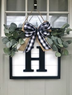 a door hanger with a monogrammed letter h and greenery on it