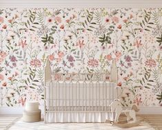 a white crib in front of a floral wallpaper