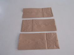 four pieces of brown paper laid out on a white surface with one piece missing from the top