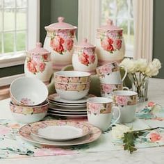 a table topped with lots of white dishes and cups covered in pink floral print on them