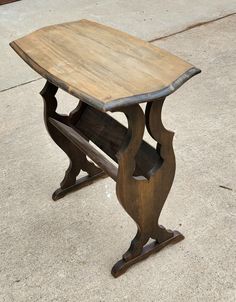 an old wooden table sitting on top of a cement floor next to a sidewalk with no one around it