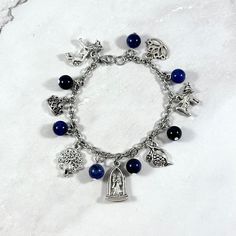 This Hera themed, charm bracelet is the perfect accessory to showcase your love for the Greek myths in a subtle way.  Hera is the Greek goddess of marriage, women, and family. She is also the queen of the gods and wife of Zeus. Charms included: Lion Crown Peacock Wedding Pomegranate  Cow Lotus 7 sodalite beads are also included between each charm.  Comes in three sizes: Small: 6.5 inches (with extra rings at the end to expand up to 7.5 inches.) Standard: 7.5 inches Large: 8.5 inches Secures with a lobster clasp. Chain is stainless steel and charms are zinc alloy. All materials are lead and nickel free. Comes in a jewelry box so it would be ready to be given as a gift! Message me of you would like to substitute any of the charms. Choking Hazard: Small parts. Not intended for small children. Spiritual Charms Bracelet For Friendship, Handmade Symbolic Charm Bracelet For Friendship, Spiritual Charms Chain Bracelet For Gift, Spiritual Sterling Silver Charm Bracelet For Friendship, Adjustable Themed Jewelry With Dangling Charms, Spiritual Chain Bracelet With Charms As Gift, Symbolic Dangle Bracelets With Charms, Spiritual Metal Beaded Bracelets For Gifts, Spiritual Metal Beaded Bracelets As Gift