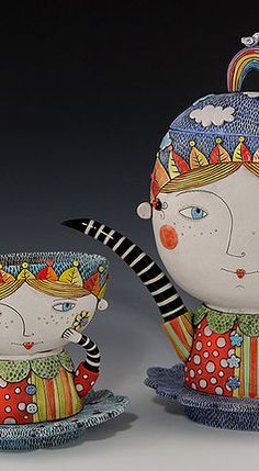 two ceramic figurines sitting next to each other on top of saucers and bowls