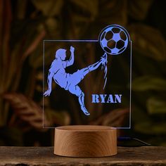 an illuminated acrylic sign with a soccer player kicking a ball