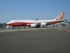 an orange and white airplane is parked on the tarmac with other planes in the background