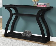 a black console table with two books on top and a white rug in front of it