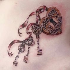 a woman's chest with an old key tattoo on it and ribbon in the shape of a heart