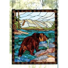 a stained glass window with a bear on the rocks in front of water and mountains