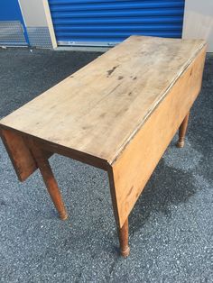 an old wooden table sitting in front of a blue garage door