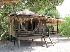 a small hut with a hammock hanging from it's roof