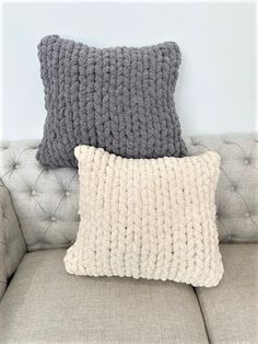 two gray and white pillows sitting on top of a couch