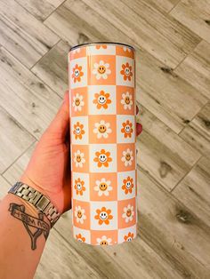 a person holding up an orange and white flowered paper tube with flowers on it