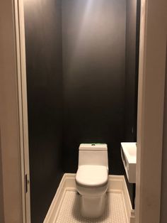 a white toilet sitting inside of a bathroom next to a sink under a light fixture