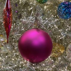 a purple ornament sitting on top of a christmas tree next to other ornaments