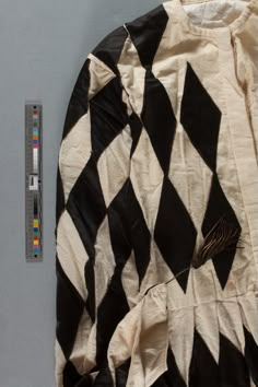 an old black and white checkered shirt next to a tape measure on the wall