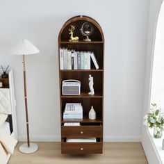 a living room with a bookcase and lamp on the floor next to a window