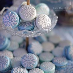 blue and white frosted cookies are on a glass platter with snowflakes