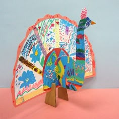 a colorful paper turkey on a pink surface