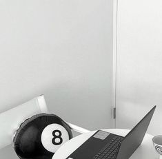 a laptop computer sitting on top of a table next to a pool ball and cup